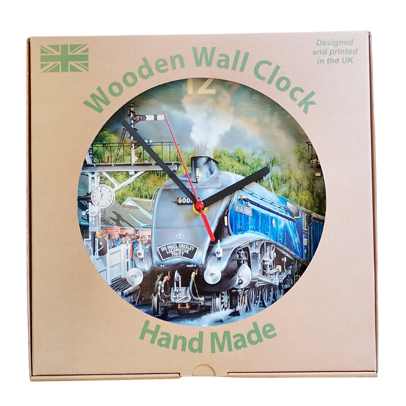 A wooden wall clock in its original packaging, featuring a circular cutout with a printed image of a steam train. The packaging is brown card with green text reading 'Wooden Wall Clock' and 'Hand Made'.