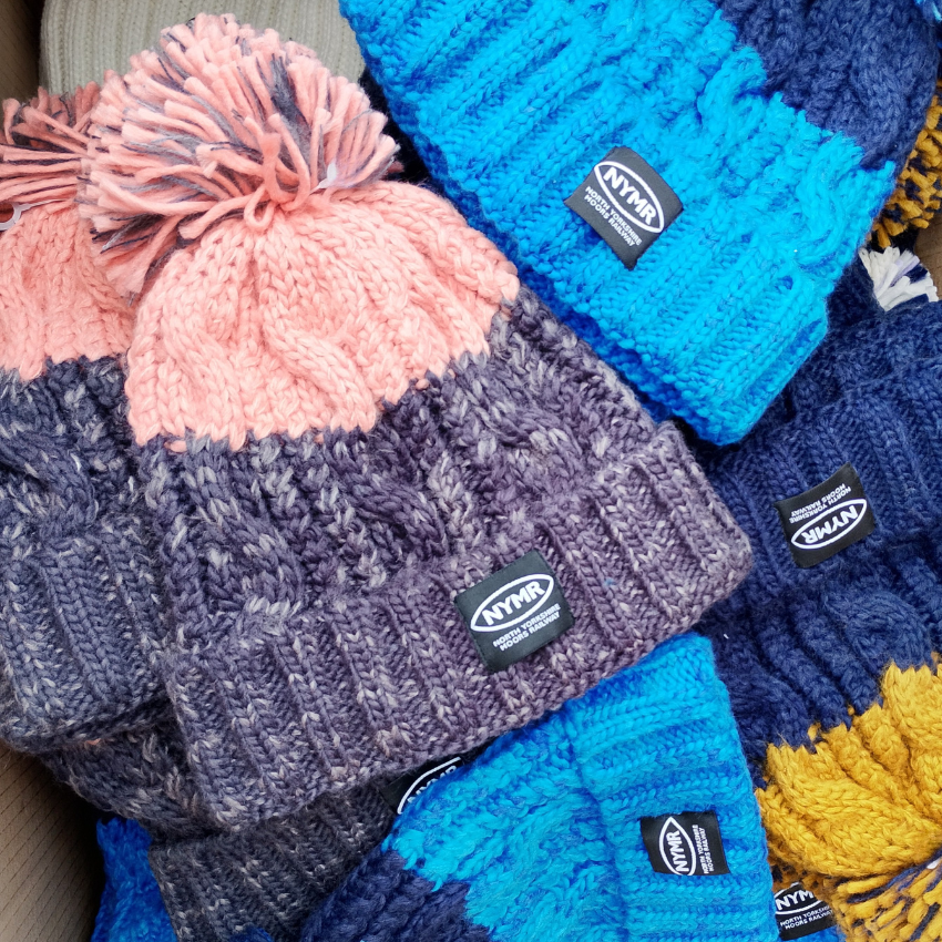 Stack of colorful knit hats with visible brand logos.