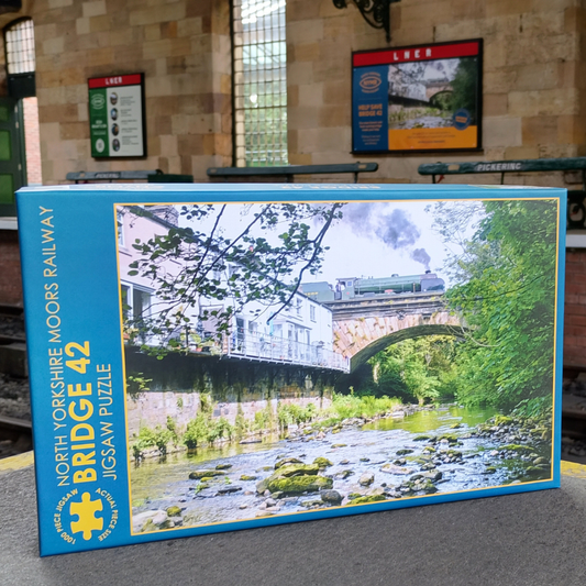 Jigsaw puzzle box featuring a scenic railway bridge with a train on it, set against the backdrop of Pickering Station.