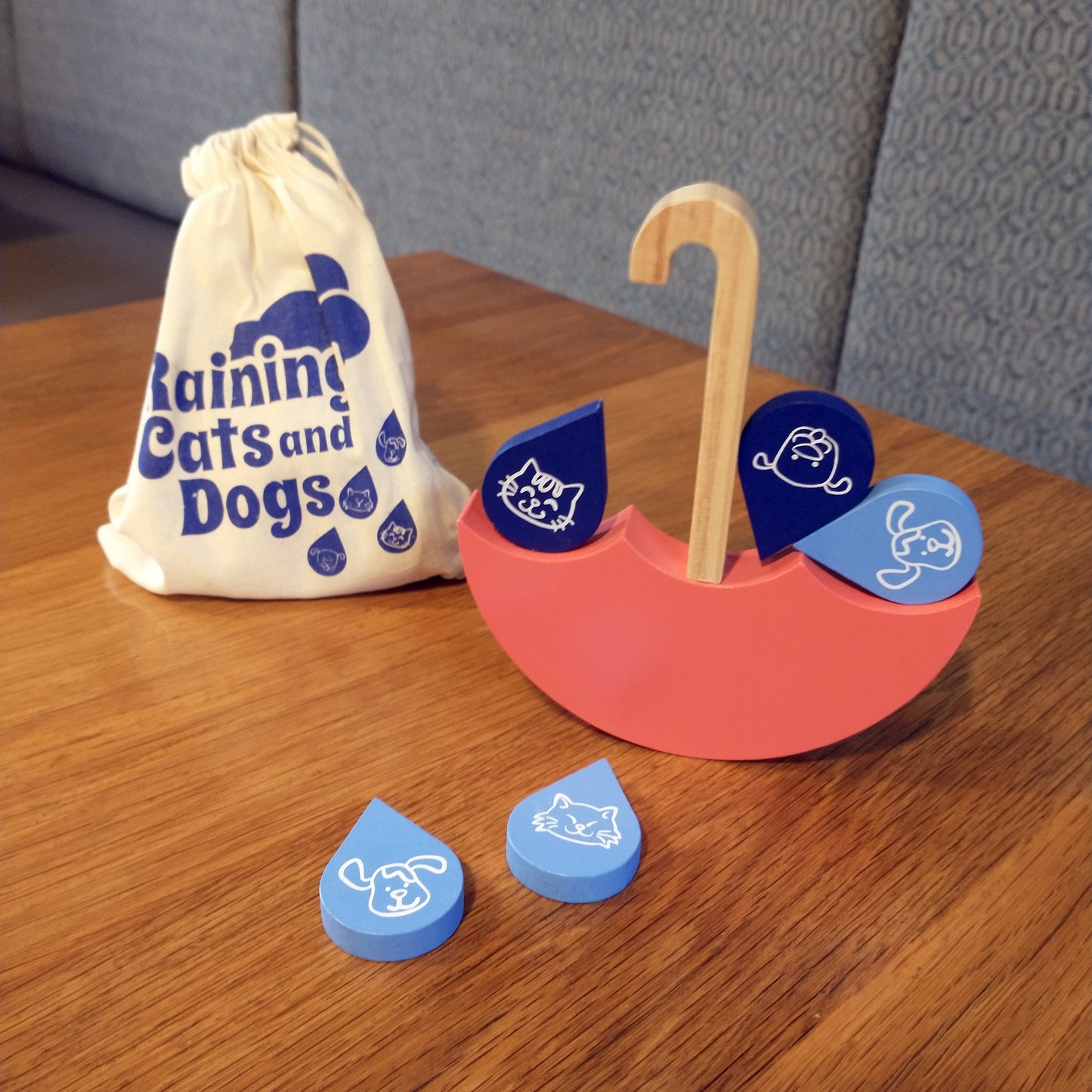 An upside down open umbrella cut out of wood and painted, with wooden raindrop shapes with cat and dog faces painted on them.
