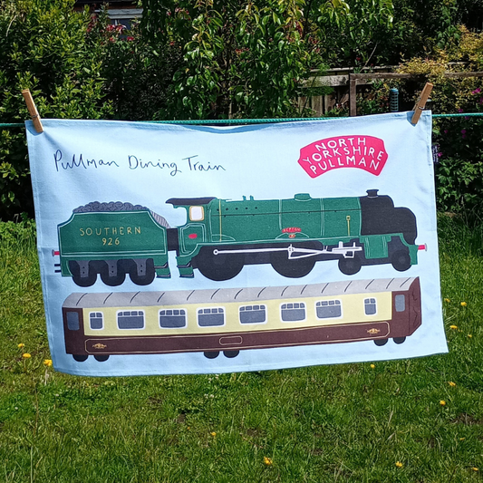 Tea towel with vintage train design on a grassy background