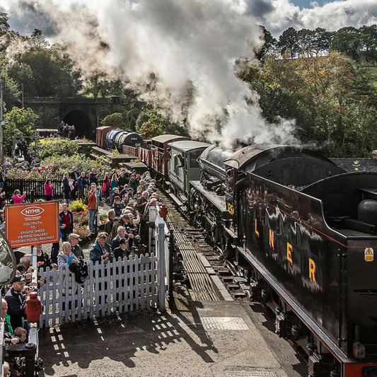Steam train passing over Bridge 42 at Grosmont surrounded by spectators.
