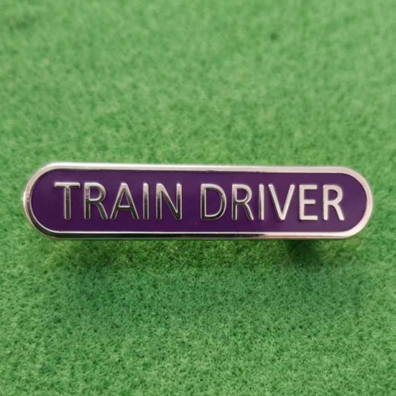 A brooch style badge with blue enamel background and silver lettering and edging.