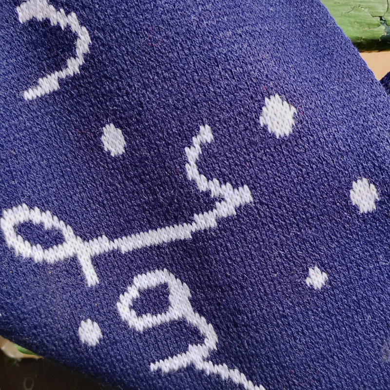 Close up of the reverse of the scarf with the lettering and snowflakes on navy.
