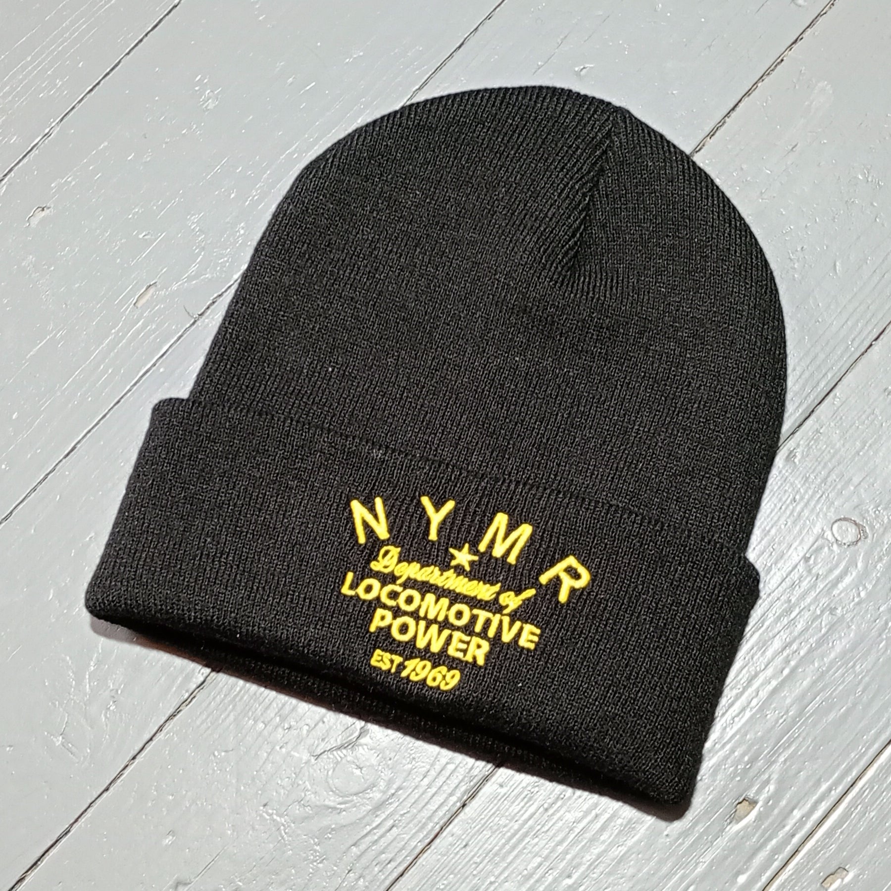 The black beanie hat with golden coloured embroidery on the front fold