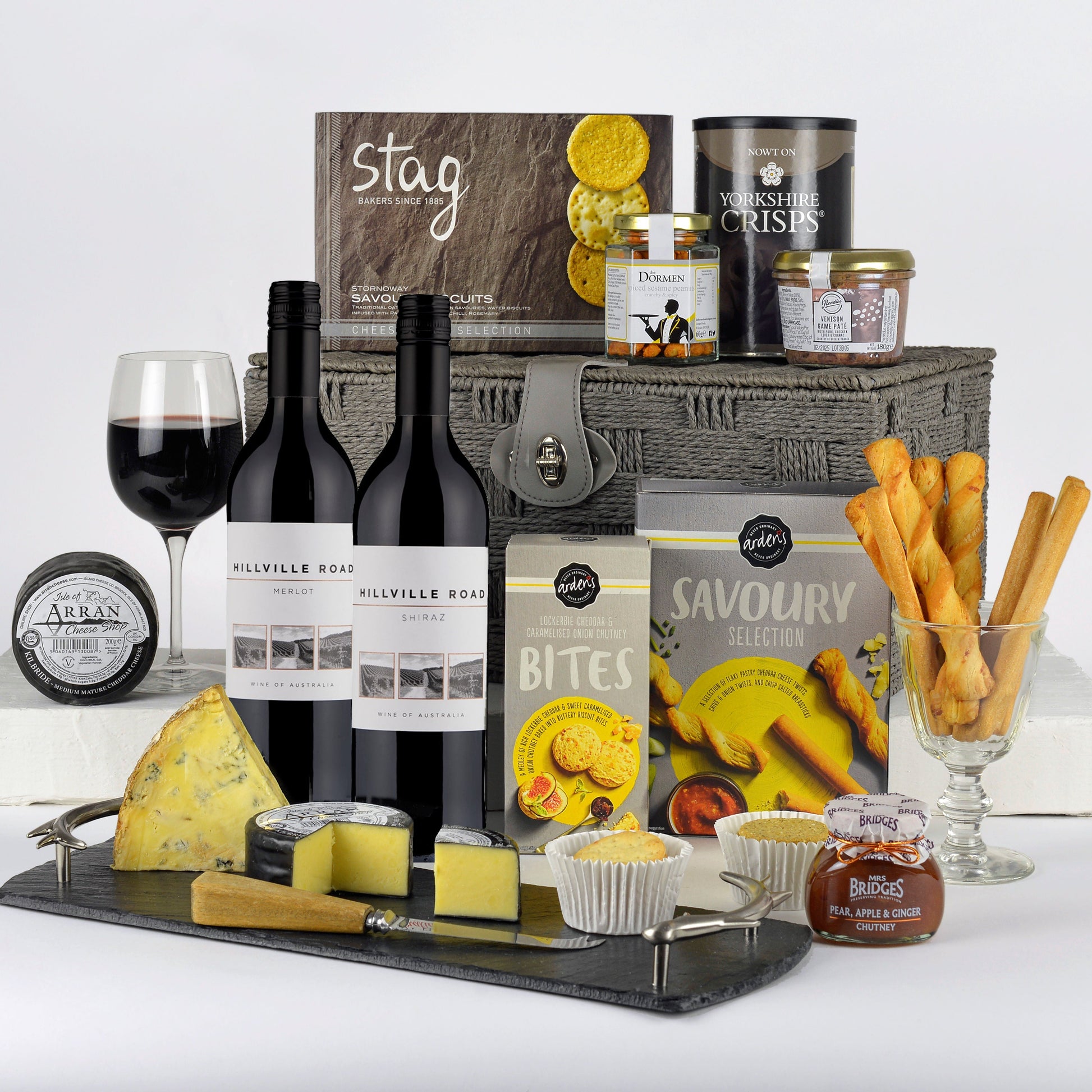 Gourmet gift basket with wine, cheese, and snacks on a white background