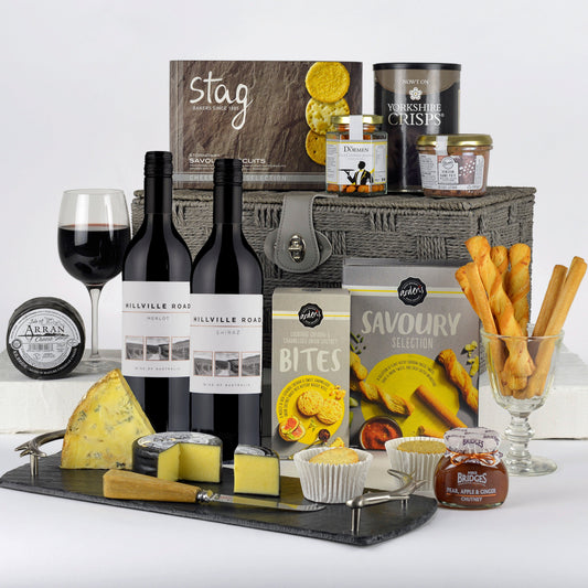 Gourmet gift basket with wine, cheese, and snacks on a white background