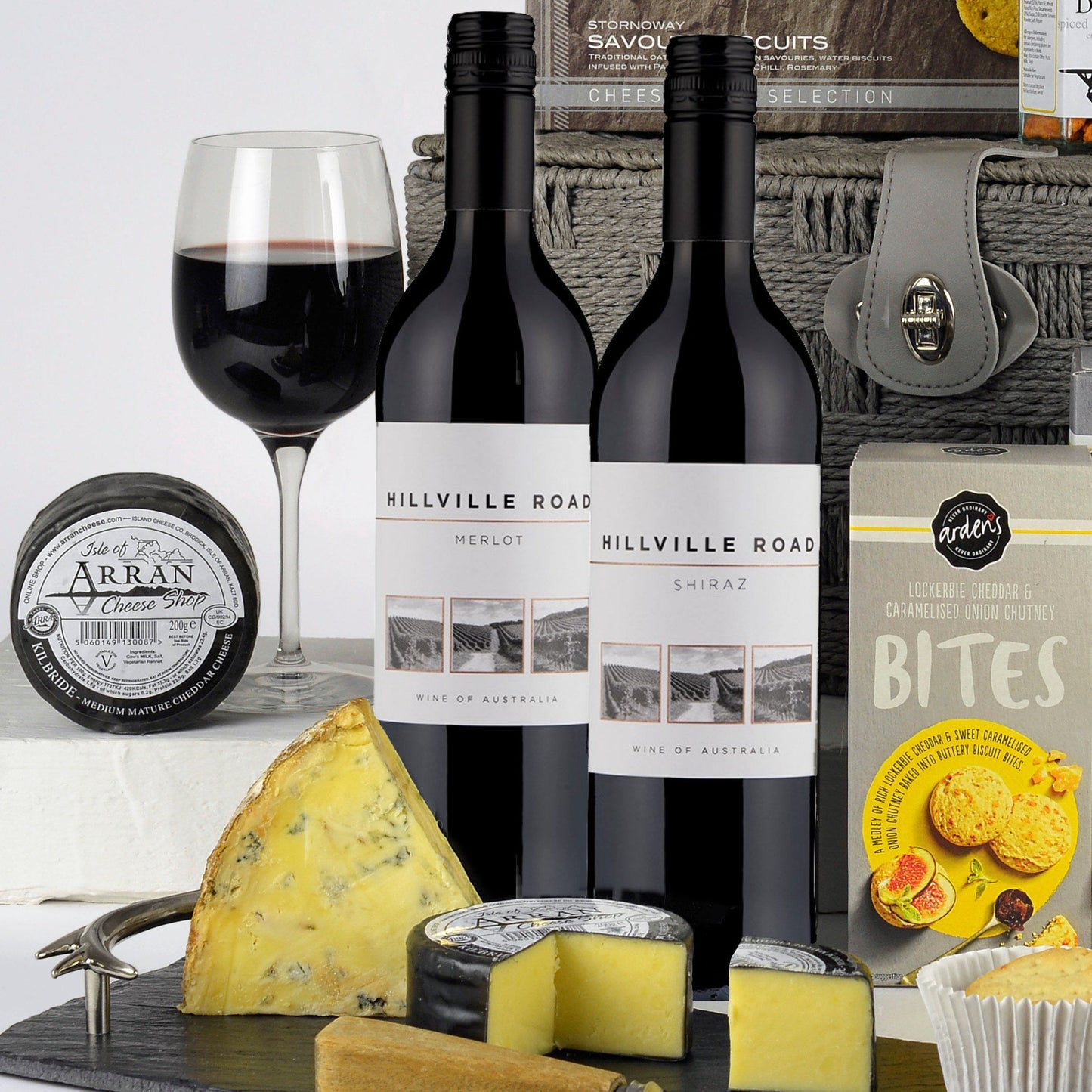 Two bottles of Hillville Road wine with a glass, cheese, and crackers on a table.
