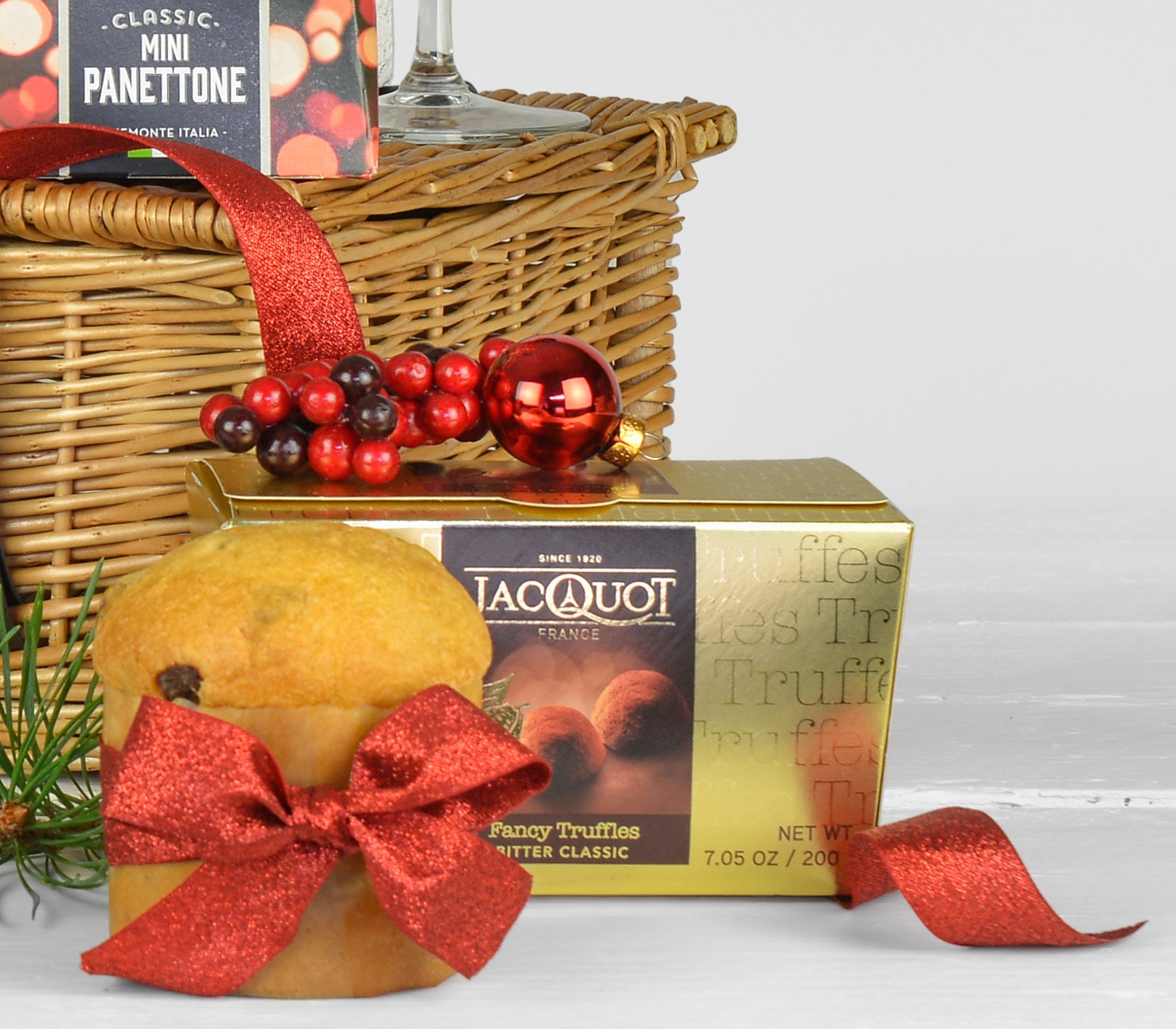 Gift basket with Jacouot truffles, a mini pannetone, and decorative elements on a white background