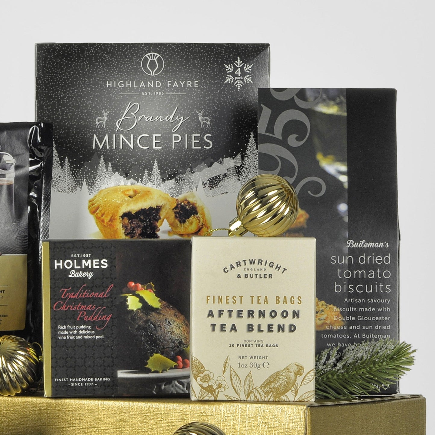 Assorted Christmas food products including mince pies, tea bags, and sun-dried tomato biscuits on a white background.