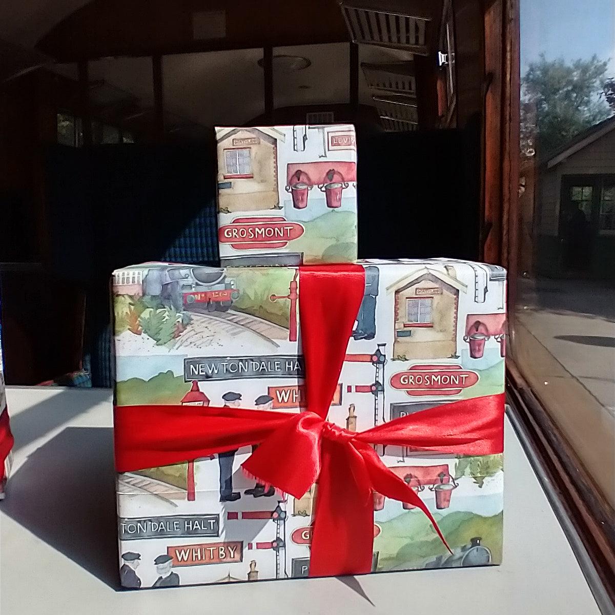 Parcels wrapped in Emma Ball wrapping paper on a table in a carriage window.
