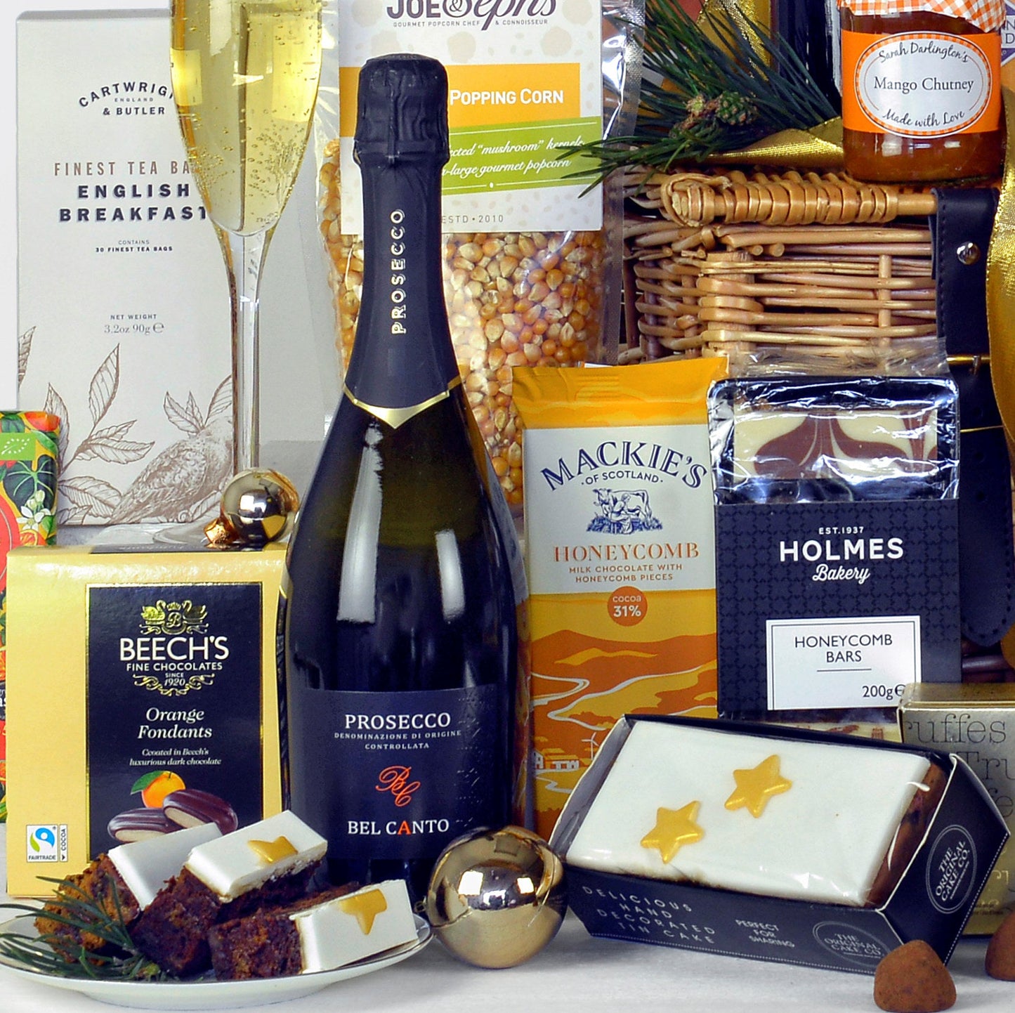 Gourmet gift basket with Prosecco, chocolate, and snacks on a white surface