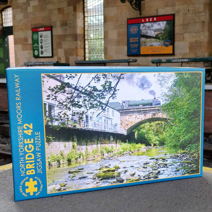 Jigsaw puzzle box featuring a scenic railway bridge with a train on it, set against the backdrop of Pickering Station.