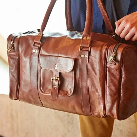 A large brown leather holdall with substantial handles , a small buckle-up side pocket and two large zipped end pockets.