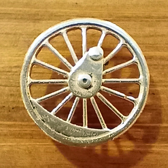 A close up of the pin, a round locomotive wheel cast in pewter.