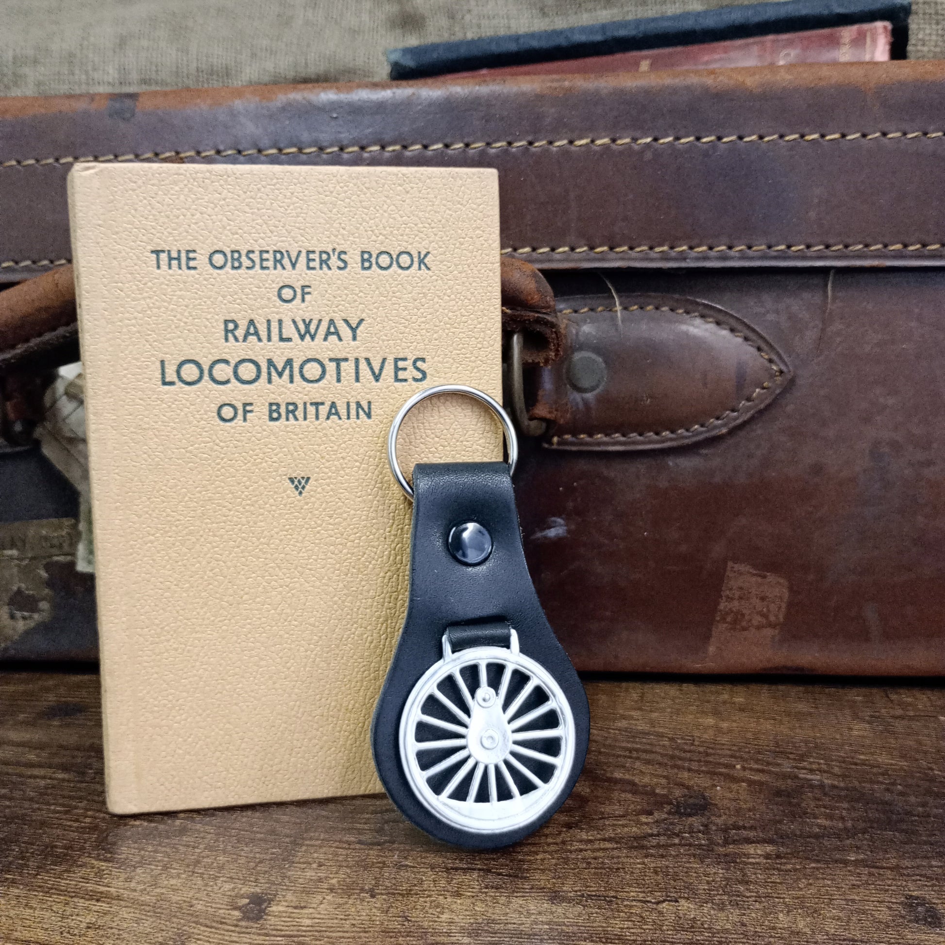 A lifestyle shot of the key fob leaning nonchalantly up against a vintage copy of the Observer's Book of Railway Locomotives and an old leather suitcase.