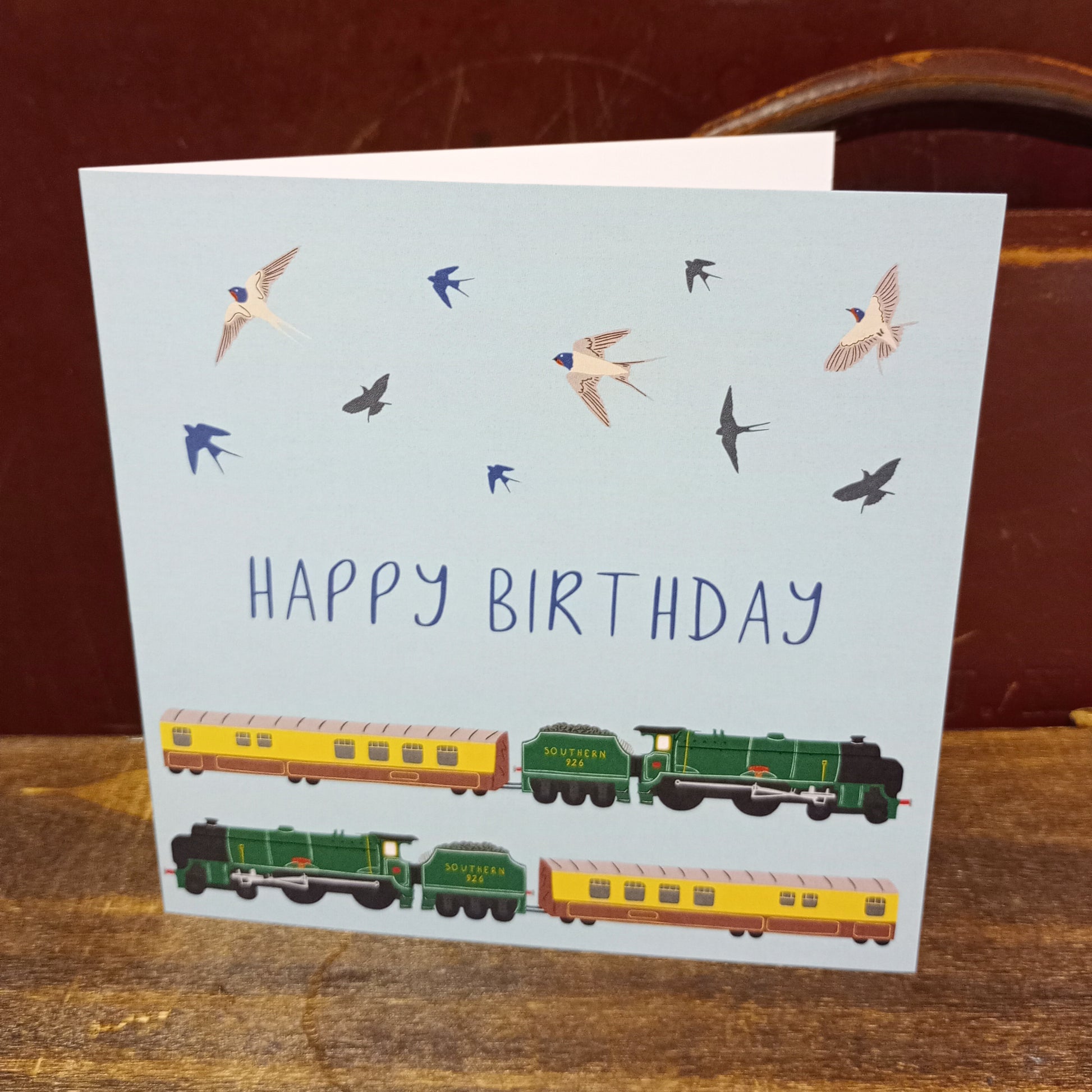 Greetings card with blue background and two dining trains, with the message Happy Birthday.