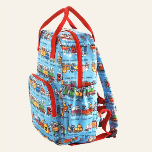 Kids backpack show from the side with a funky trains design on a blue background and contracting red straps, handles and zips.
