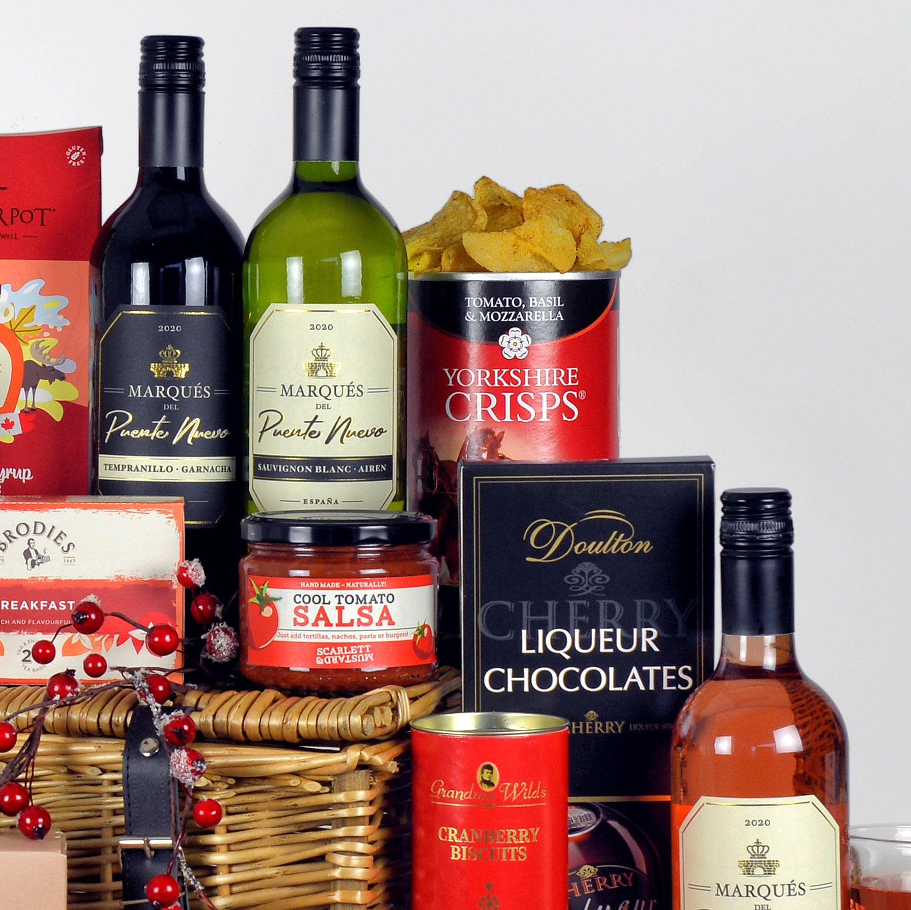 Assorted food and drink items including wine, crisps, chocolates, and preserves in a basket.
