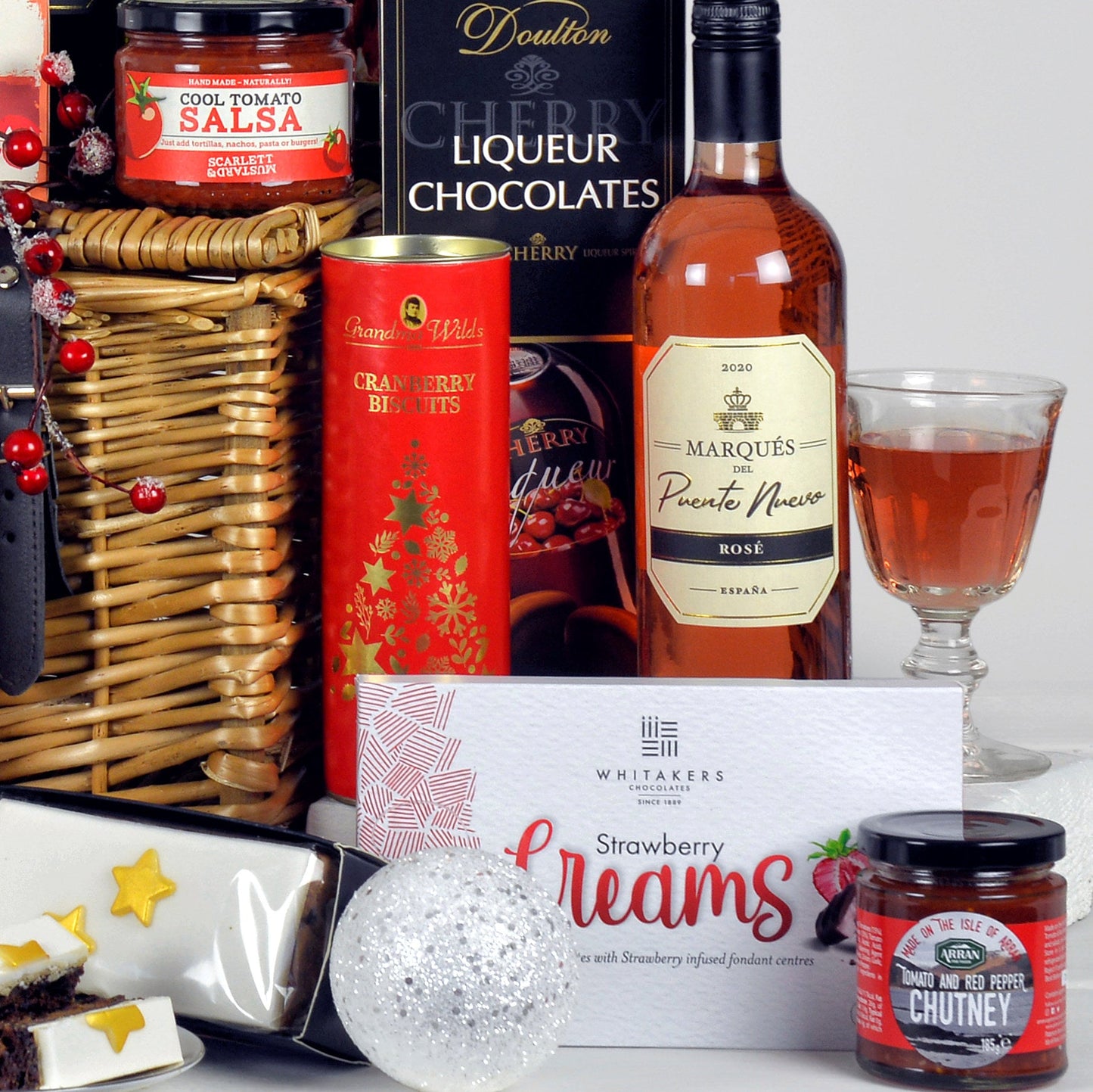 Gourmet gift basket with wine, chocolates, and other treats on a white background
