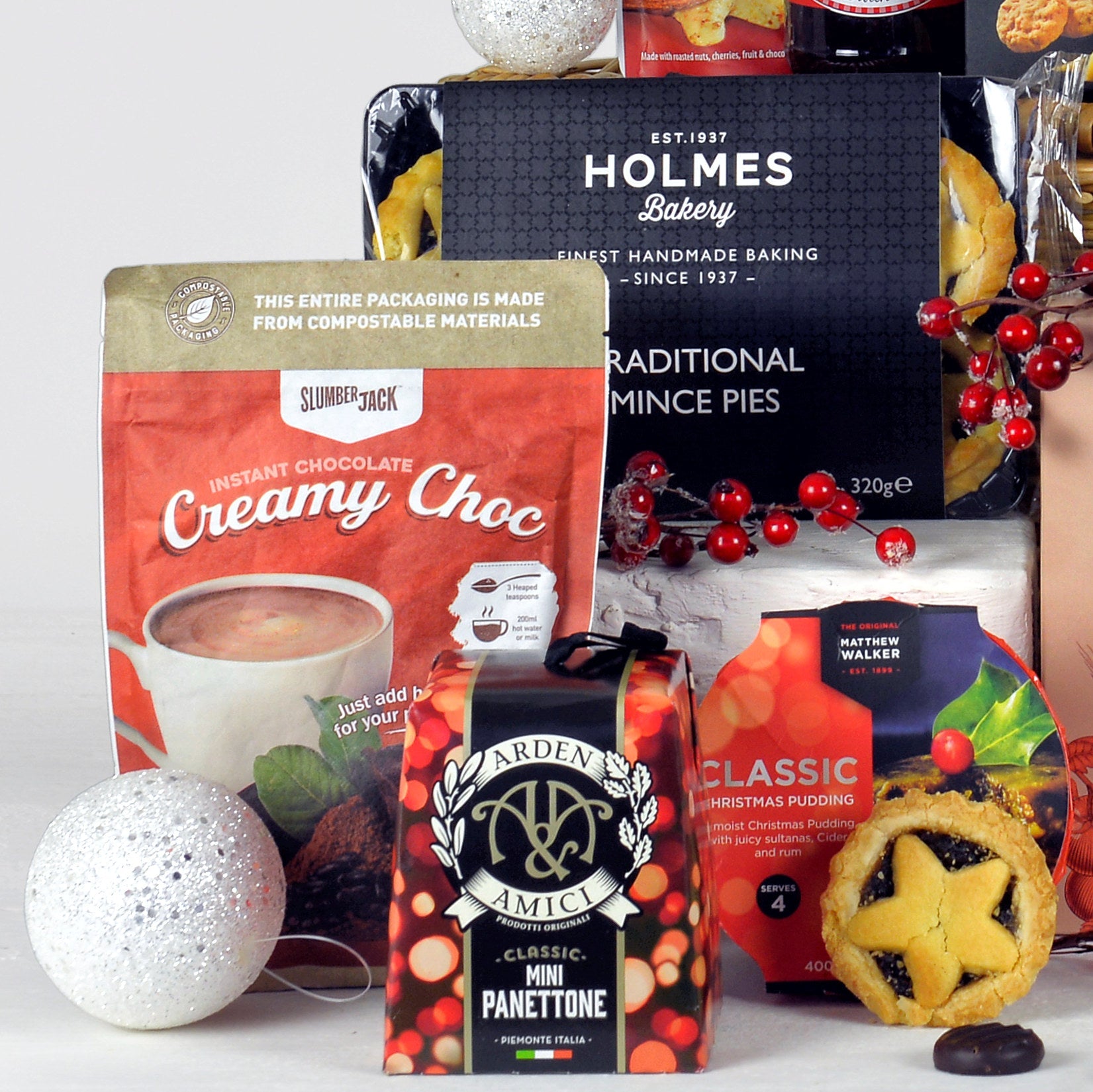 Collection of Christmas-themed products including mince pies, a mini panettone, and hot chocolate on a white background.