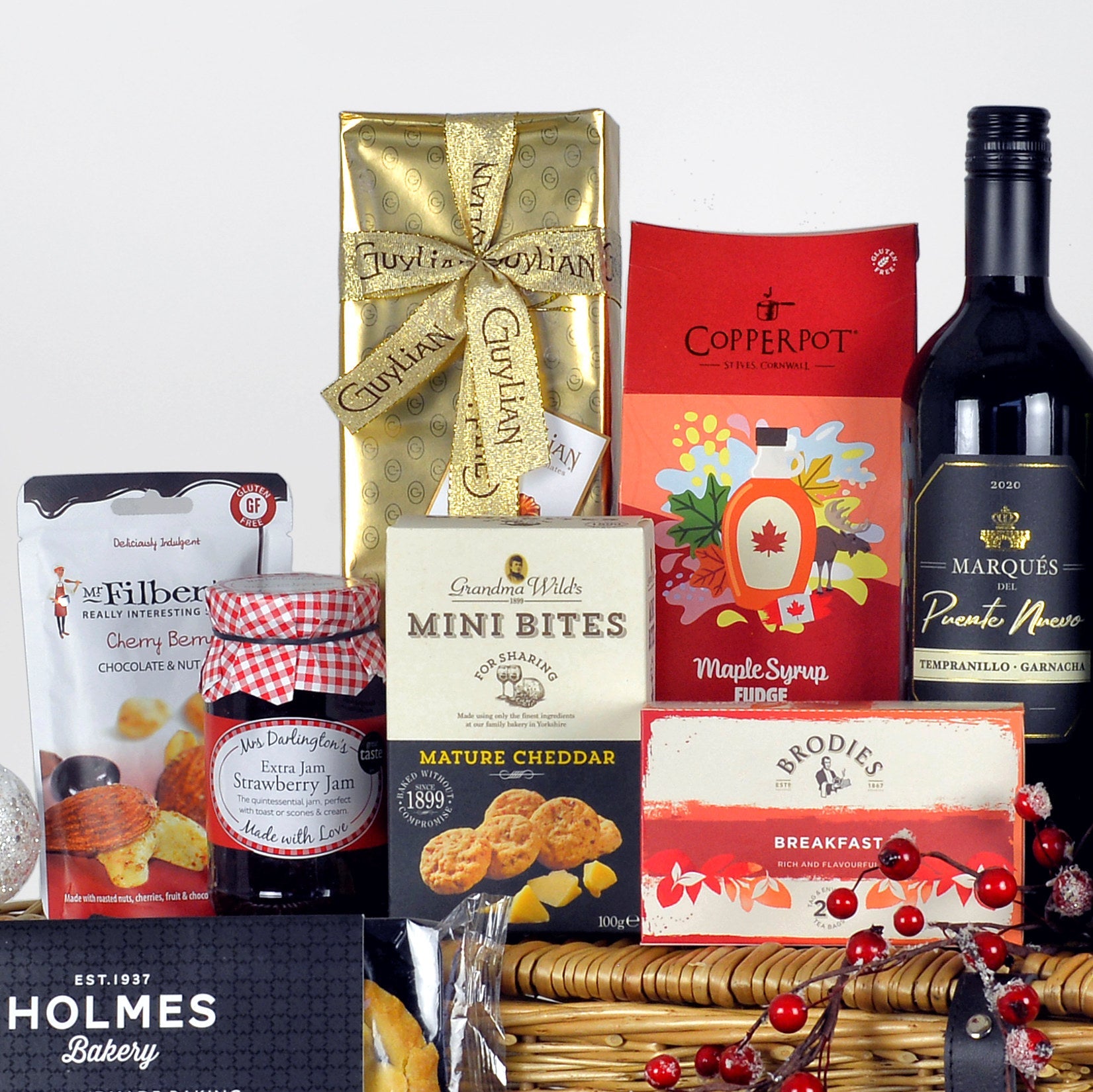 Assorted gourmet food items including a bottle of red wine, Guylian chocolates, and packaged snacks on a white background.