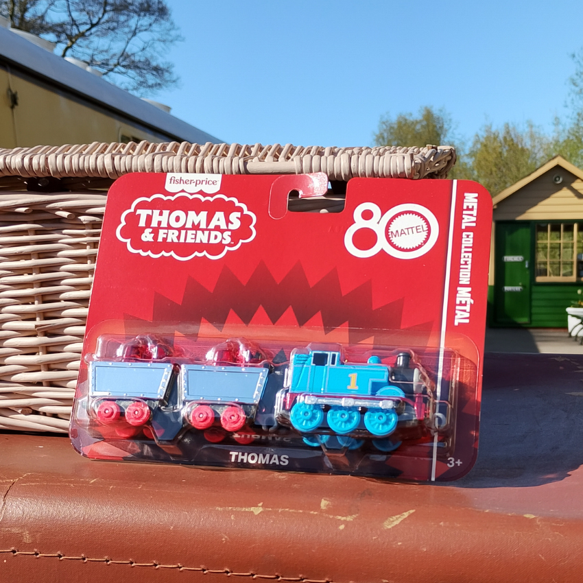Toy train set in packaging with 'Thomas & Friends' branding on a red surface.