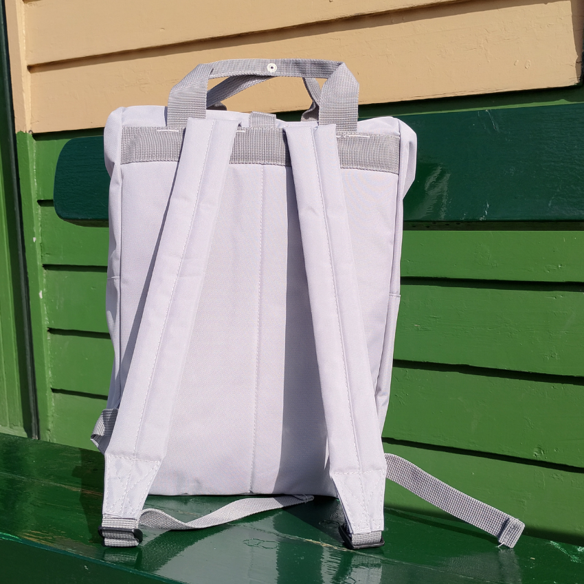 Grey backpack taken from the back so you can see the straps on a green bench