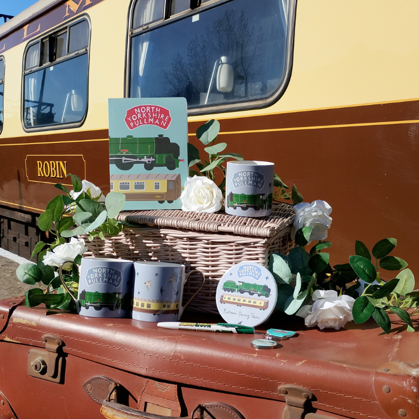 Decorative setup with a wicker basket, mugs, and a sign on a vintage train car.