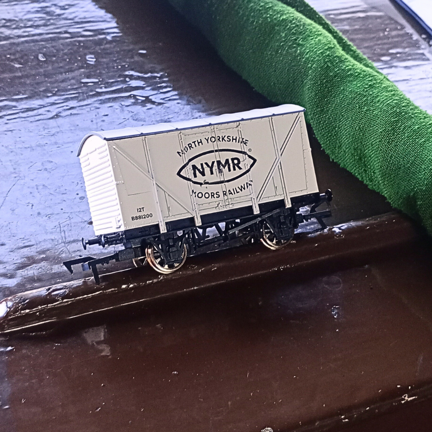 Model train car with 'NORTH YORKSHIRE MOORS RAILWAY' branding on a reflective surface.