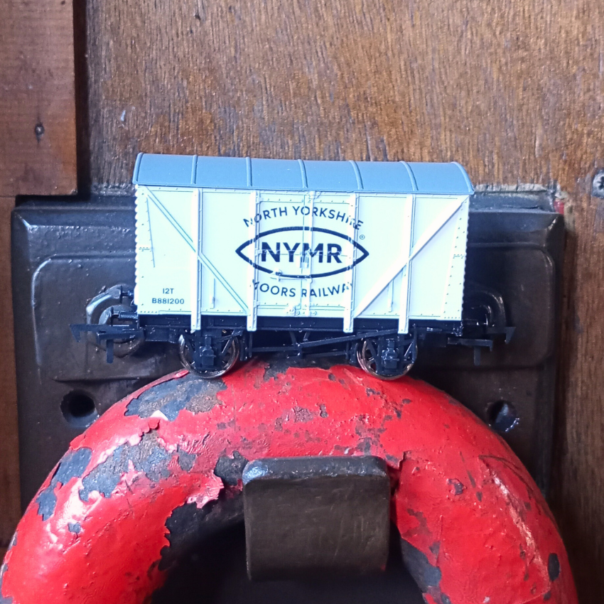 Model train car with 'NYMR' branding on a white wooden background