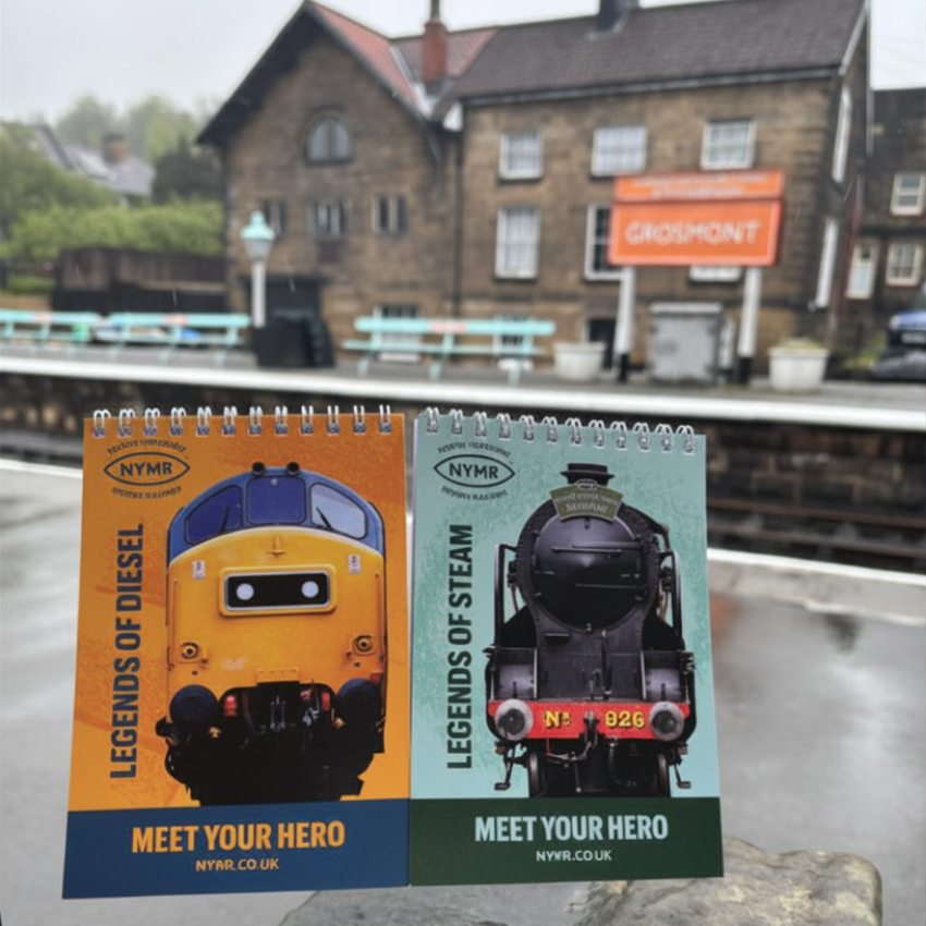 Two train-themed notebooks with locomotive images on a platform background.