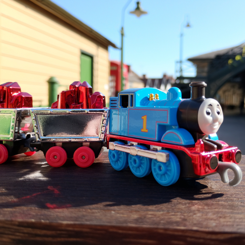 Toy train with a blue engine and red cars on a wooden surface