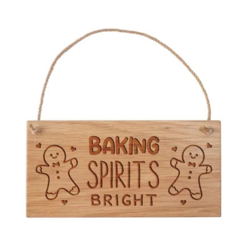 Wooden sign with 'Baking Spirits Bright' text and gingerbread man designs on a white background