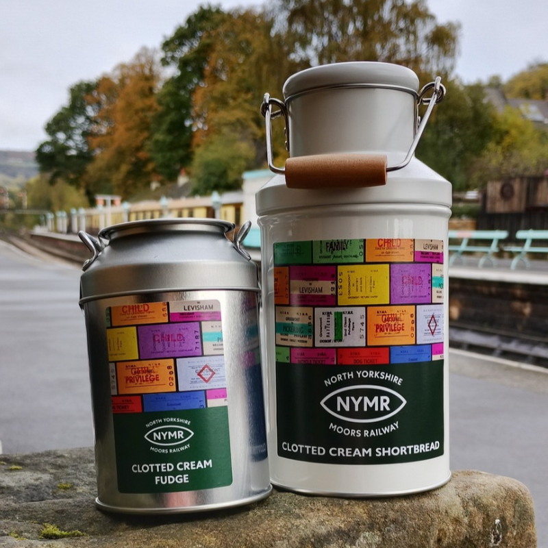 A small silver coloured churn and cream coloured churn on Grosmont station