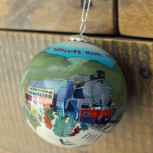 Christmas bauble with coloured painting of steam train with Yorkshire Moors Railway written in red in the sky round the top