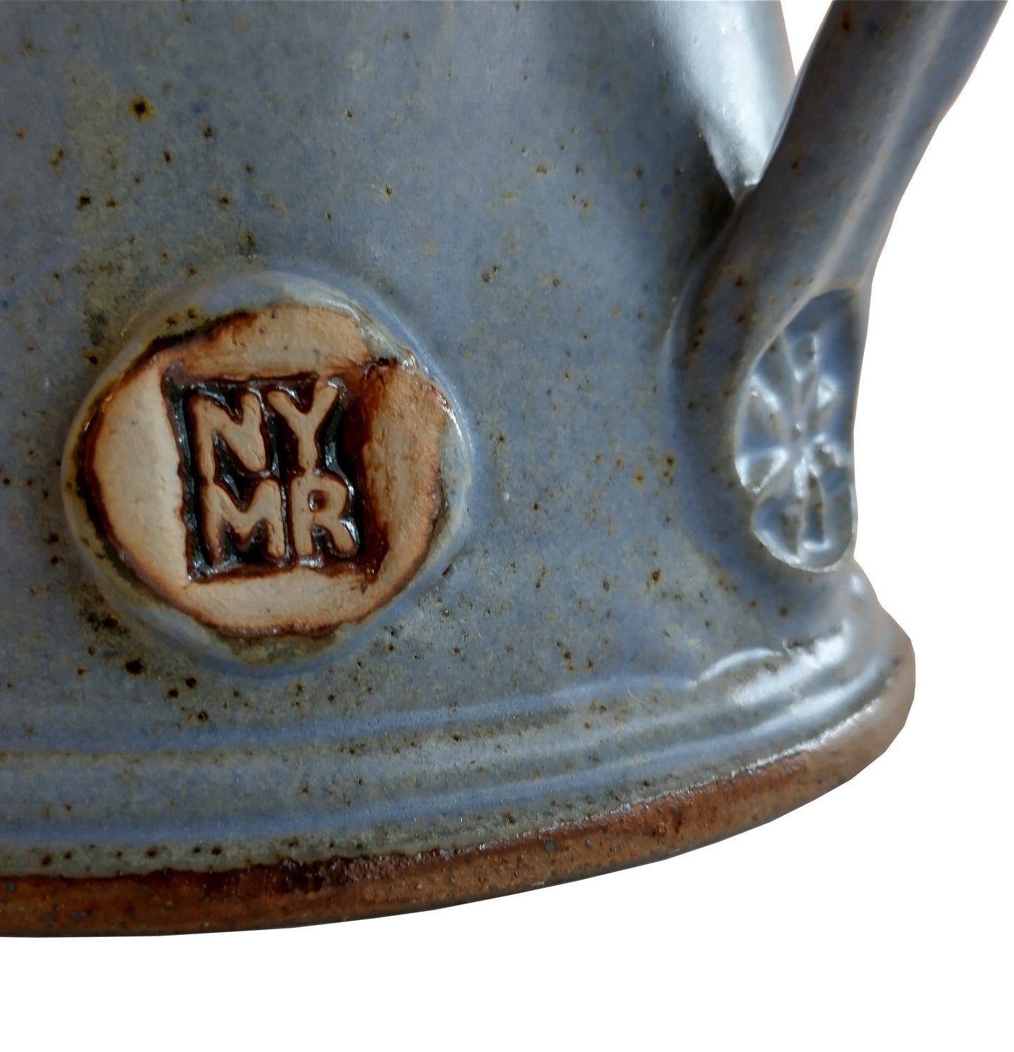 Close up of N Y M R near bottom of handle on matt light blue tankard.