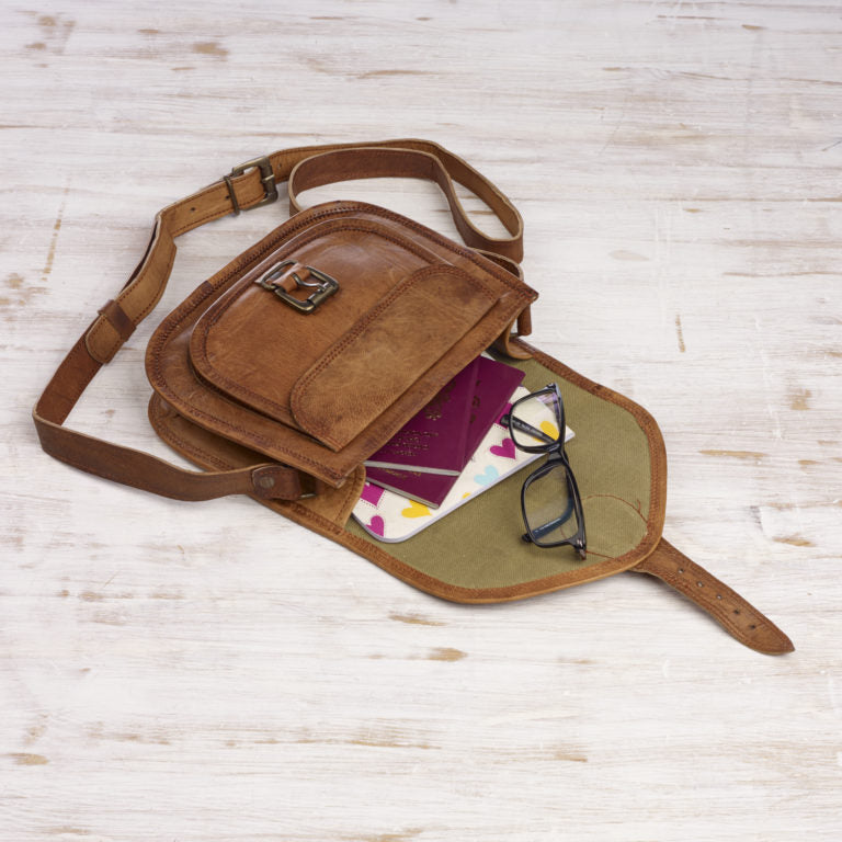 Small tan leather shoulder bag showing inside with space for passports and glasses.
