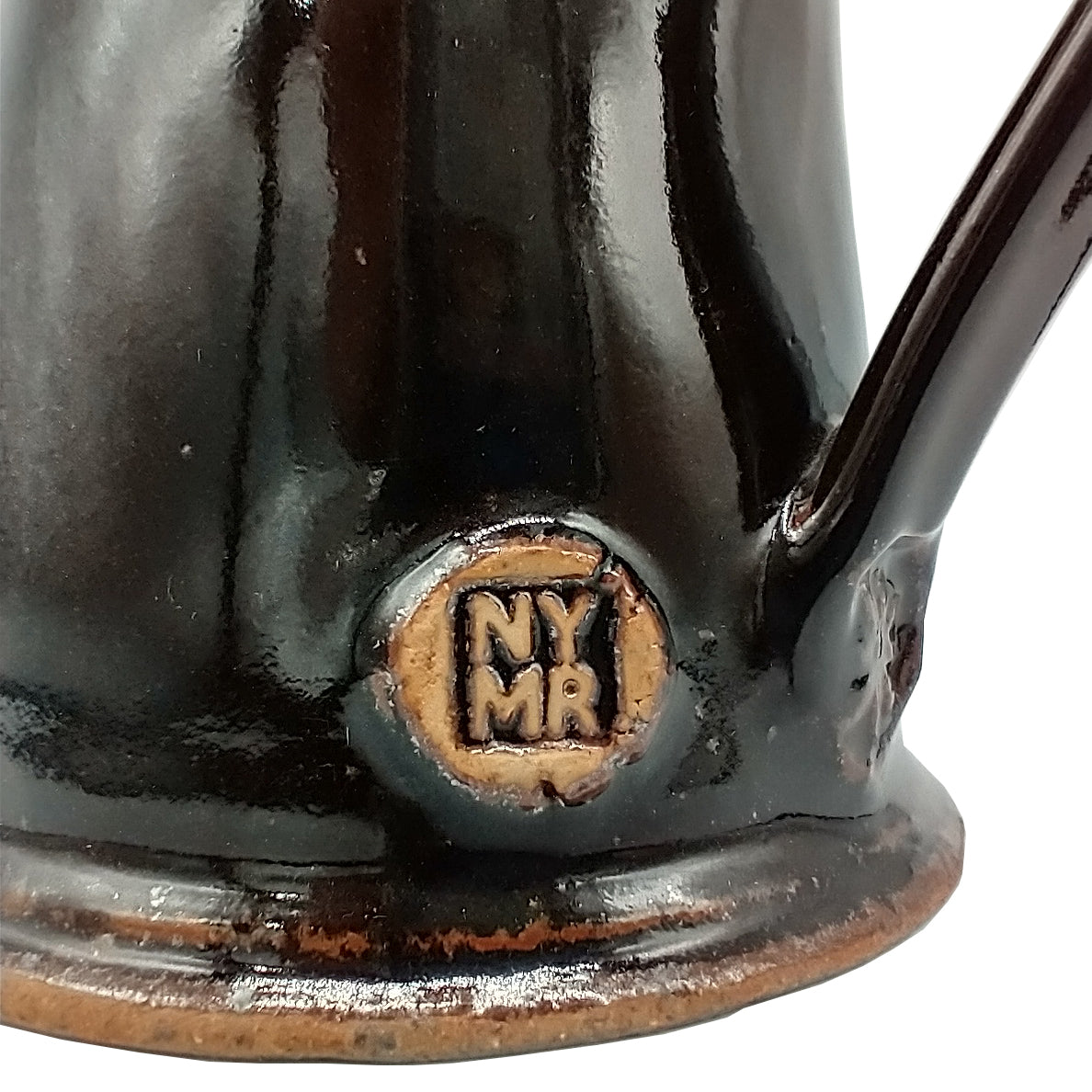 Close up of N Y M R near bottom of handle on black tankard.