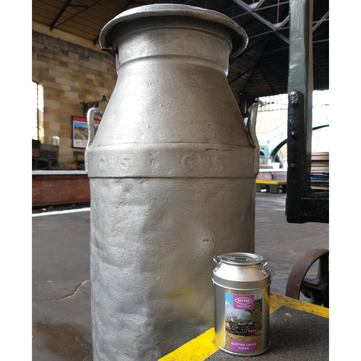 A metal fudge churn stood next to a full size vintage milk churn on Pickering Station.