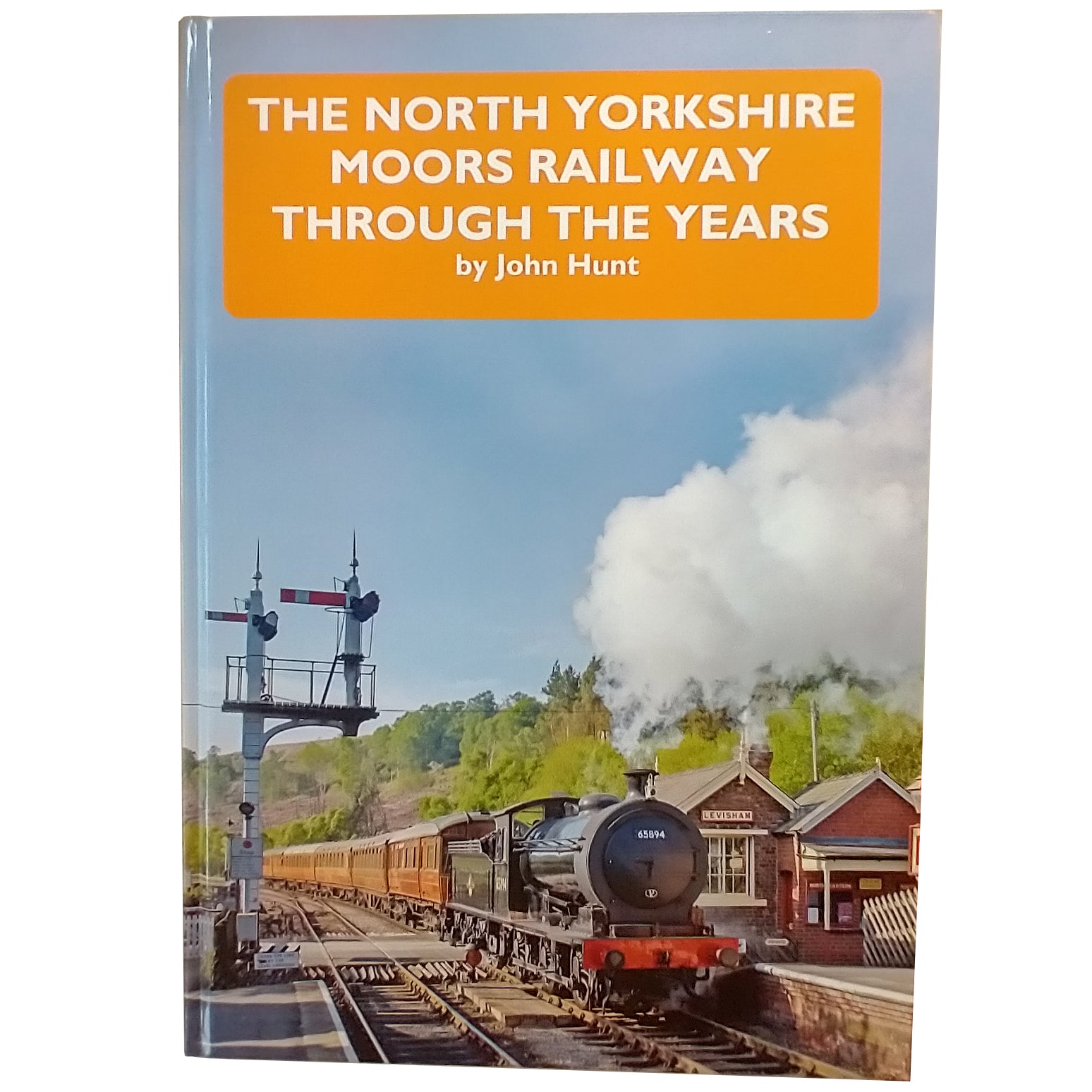 Hard back book cover with photograph of the steam engine 65894 pulling the teak carriages through Levisham Station.  The North Yorkshire Moors Railway Through the Years by John Hunt printed in white on a yellow block at the top of the picture.