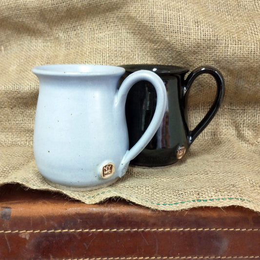 Two hand thrown pottery mugs - one in pale blue and one in black glaze finish.